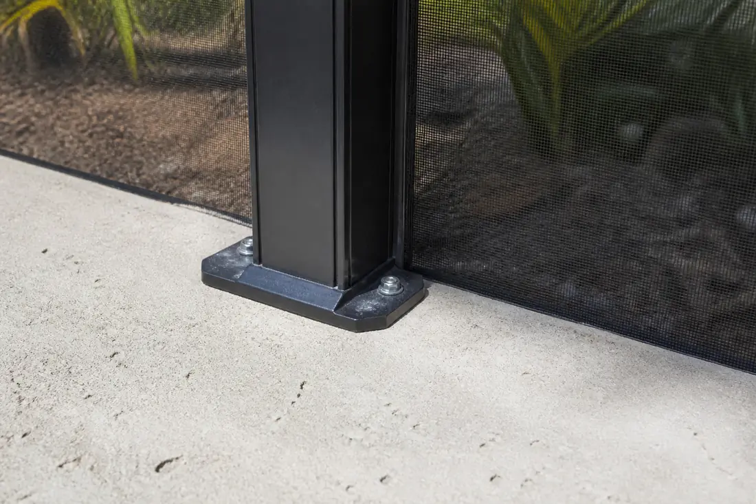 The base of a screen enclosure column bolted to a pool deck with the screen meeting the deck