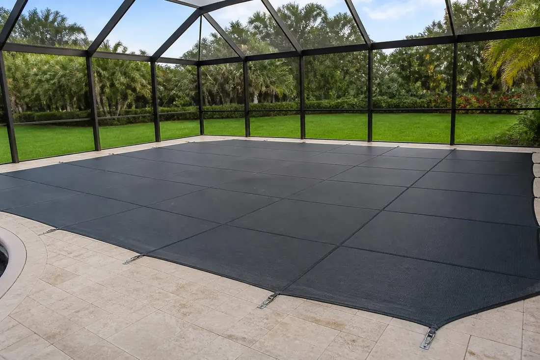 A tensioned safety cover drawn taut across a residential swimming pool inside a screened enclosure
