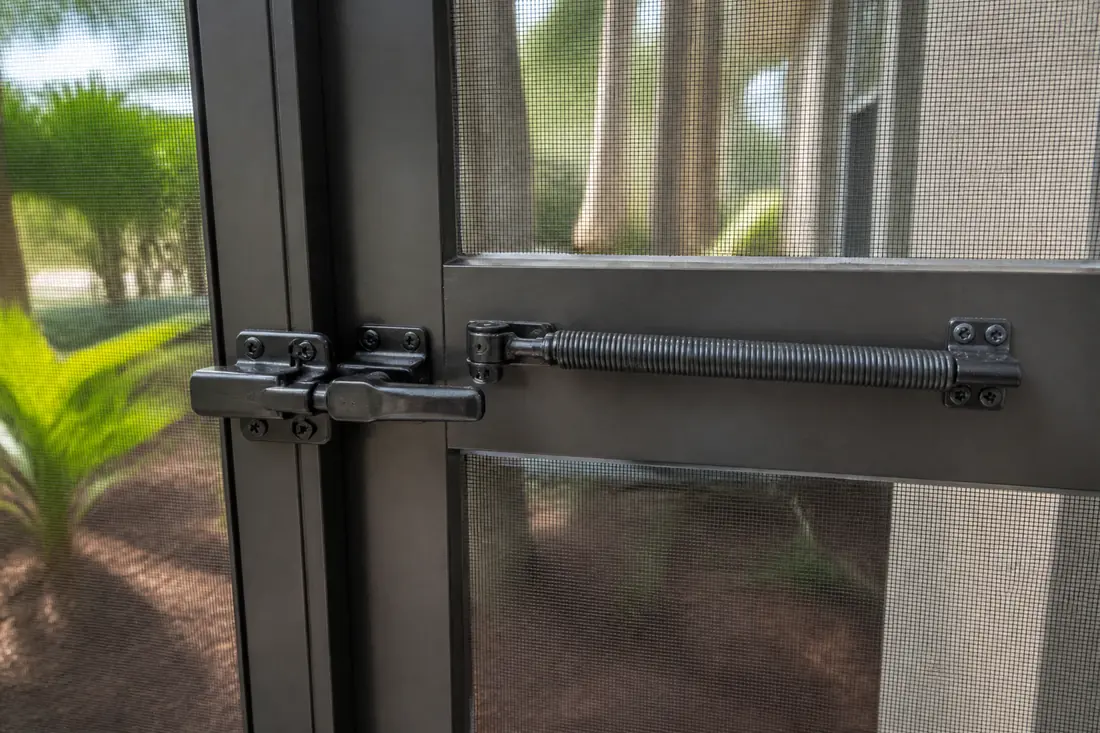 The latch and closer hardware on a screen enclosure access door