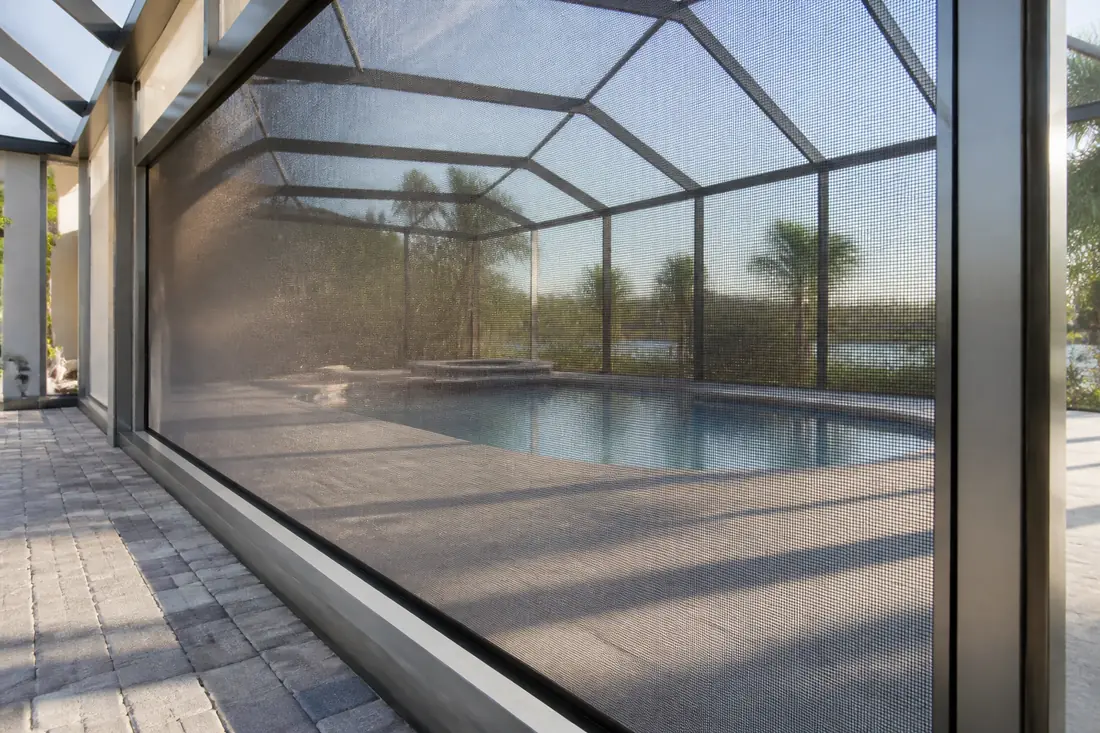 A screen panel in a pool enclosure frame with the pool visible through it